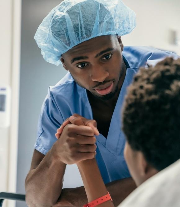 Male doctor holding the hand of patient in critical care setting