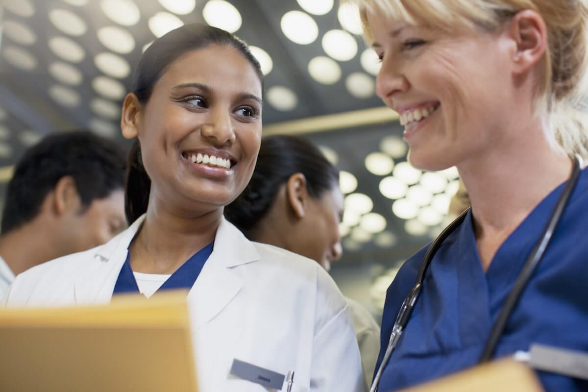 Smiling woman physician and woman nurse in hospital hallway