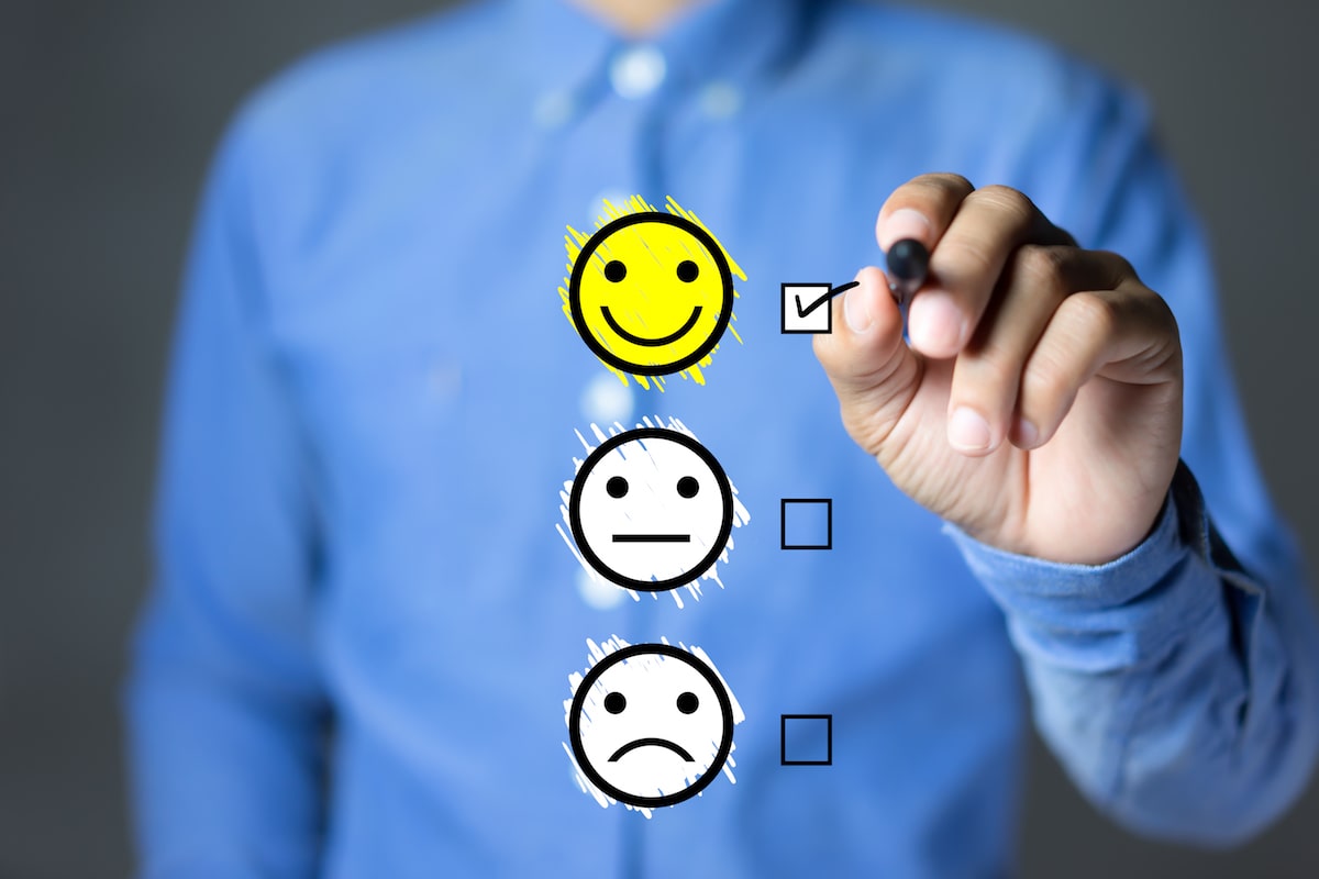 man in blue shirt filling out satisfaction survey with smiley faces