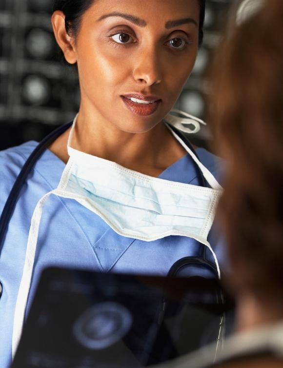 Neurohospitalist physician with white mask around neck looks concerned