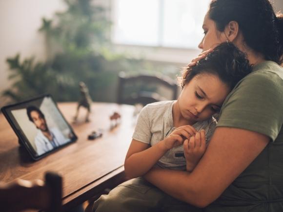 Mother and child using teleurgent care to speak with doctor using a tablet